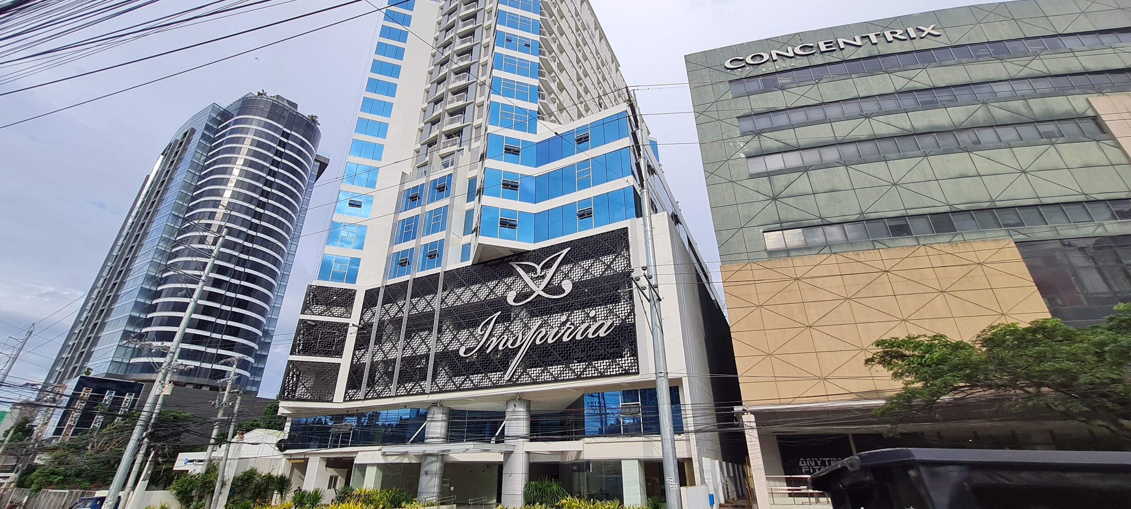 Un edificio moderno con un llamativo letrero que dice 'Inspiration', rodeado de otros edificios de gran altura.