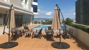 A rooftop pool area with lounge chairs and umbrellas, overlooking a cityscape. - Inspiria Condo Units beside Abreeza Mall Davao (Davao)