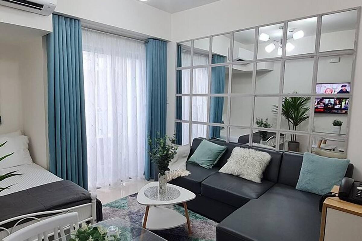 Un salon moderne avec un canapé, une petite table basse et un téléviseur fixé sur une cloison en verre.