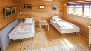 Een gezellig kamer in chaletstijl met twee bedden, een kleintje tafeltje en houten wanden.