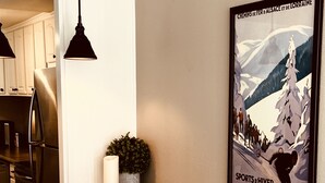 Et køkken med en træbordplade, en mørk stol og et indrammet plakat på væggen.
