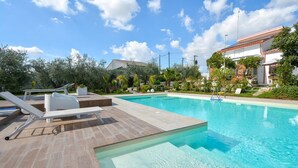 En swimmingpool med liggestole og en lille solterrasse.