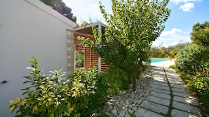 En have med beboelse, swimmingpool, stentrappe og forskellige planter.