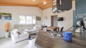 Et moderne køkken med en central ø, et spiseområde med bord og stole, en sofa og en pejs.