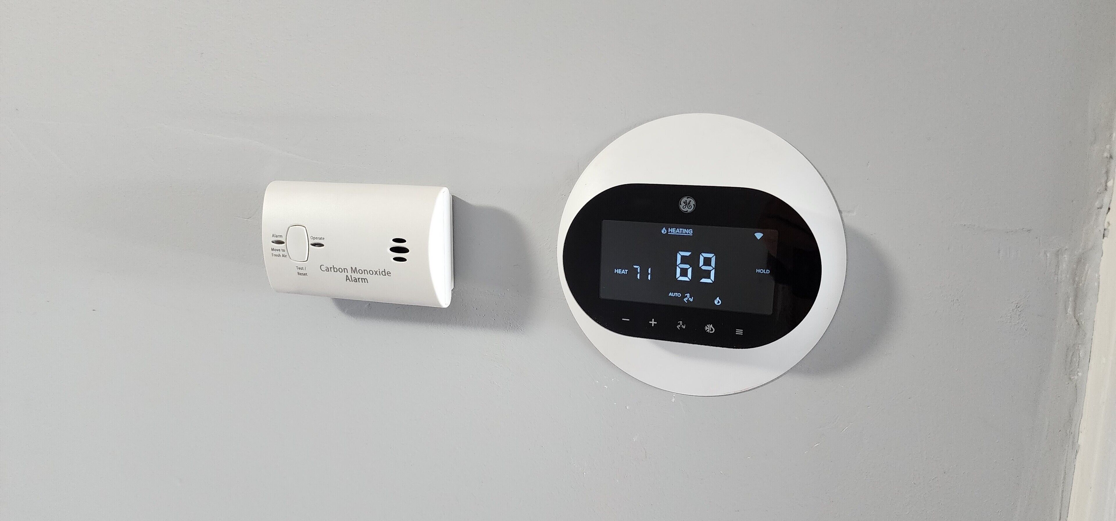 A thermostat and a carbon monoxide alarm on a wall.