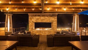 An outdoor patio with stone fireplace, wicker furniture, and string lights. - Moab Sage Creek Vista Views (Moab)