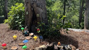 Escena de bosque con un estanque, rocas y decoraciones de hongos coloridos.