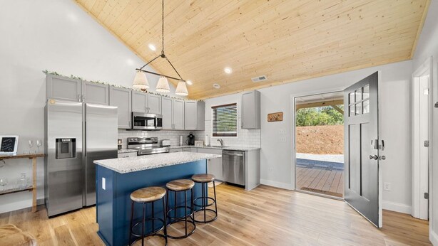 Una cocina moderna con una isla central, electrodomésticos de acero inoxidable y techo de madera.