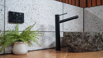 A kitchen with a modern faucet, a potted fern, and a stone countertop.