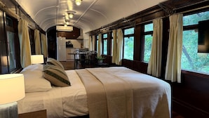Un compartiment-chambre dans un train, avec un lit, un bureau et une vue sur la forêt par les fenêtres.