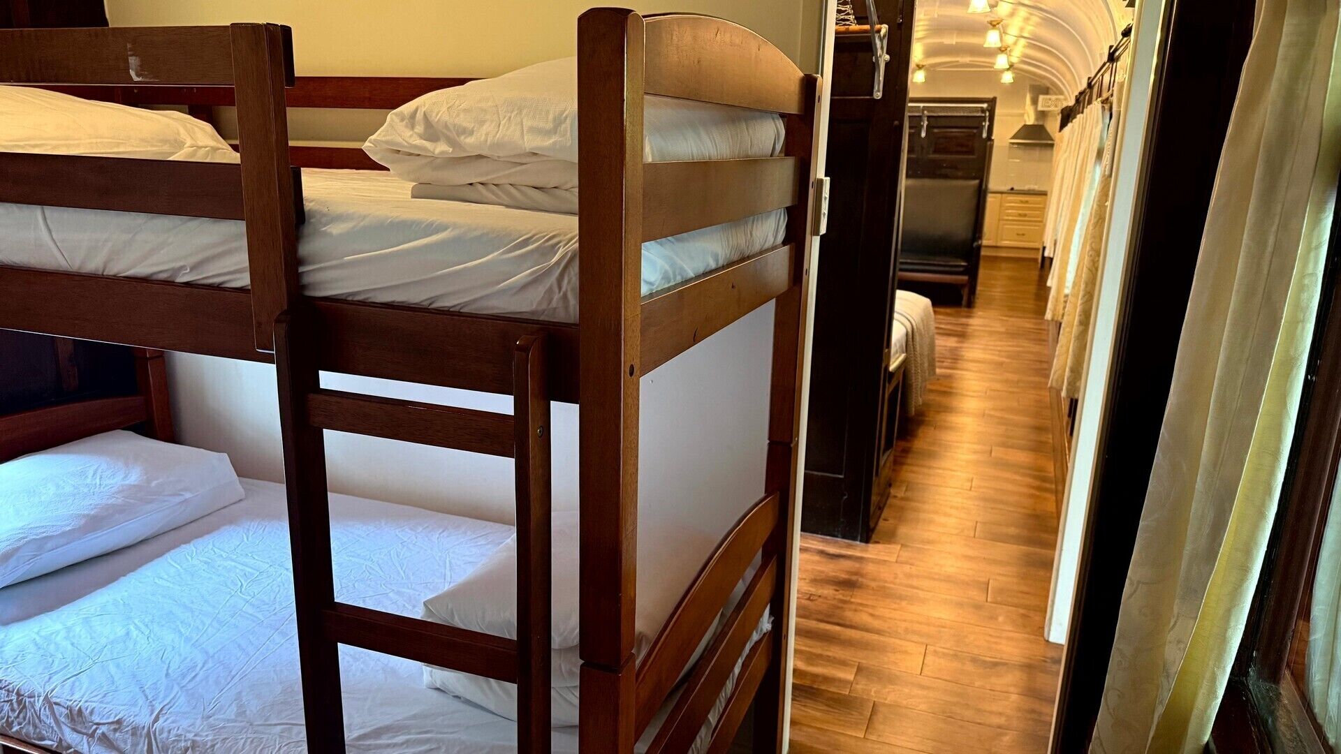 A narrow corridor with bunk beds on one side and a kitchenette on the other.