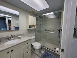 Une salle de bain moderne avec une douche à parois de verre, des toilettes blanches et un lavabo en marbre.