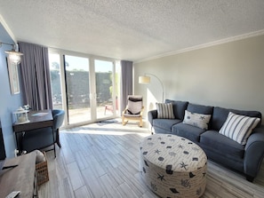 Un salon moderne comprenant un canapé, un pouf et un coin repas avec une table et des chaises.