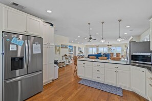 Una cocina moderna con armarios blancos, electrodomésticos de acero inoxidable y una isla central con asientos.