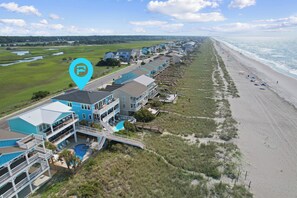 A beachfront property with multiple buildings, a swimming pool, and a beach. - "A Perfect Landing" is a 6 Bedroom / 6.5 Bath Home w/ Private Pool & Elevator. (Holden Beach)