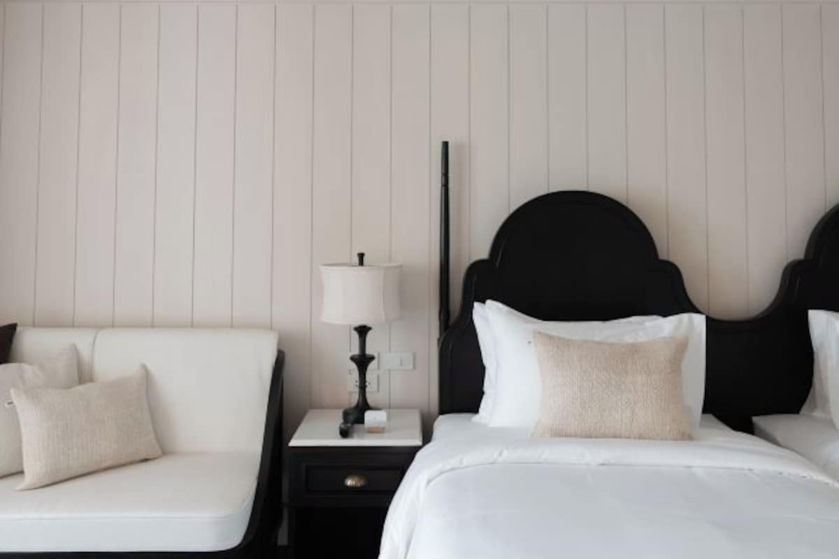 Una habitación de hotel con una cama, una mesita de noche, una lámpara y un sofá.