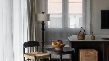 Una habitación moderna con una mesa de comedor, sillas, una lámpara, una cesta de fruta y un televisor en la pared.