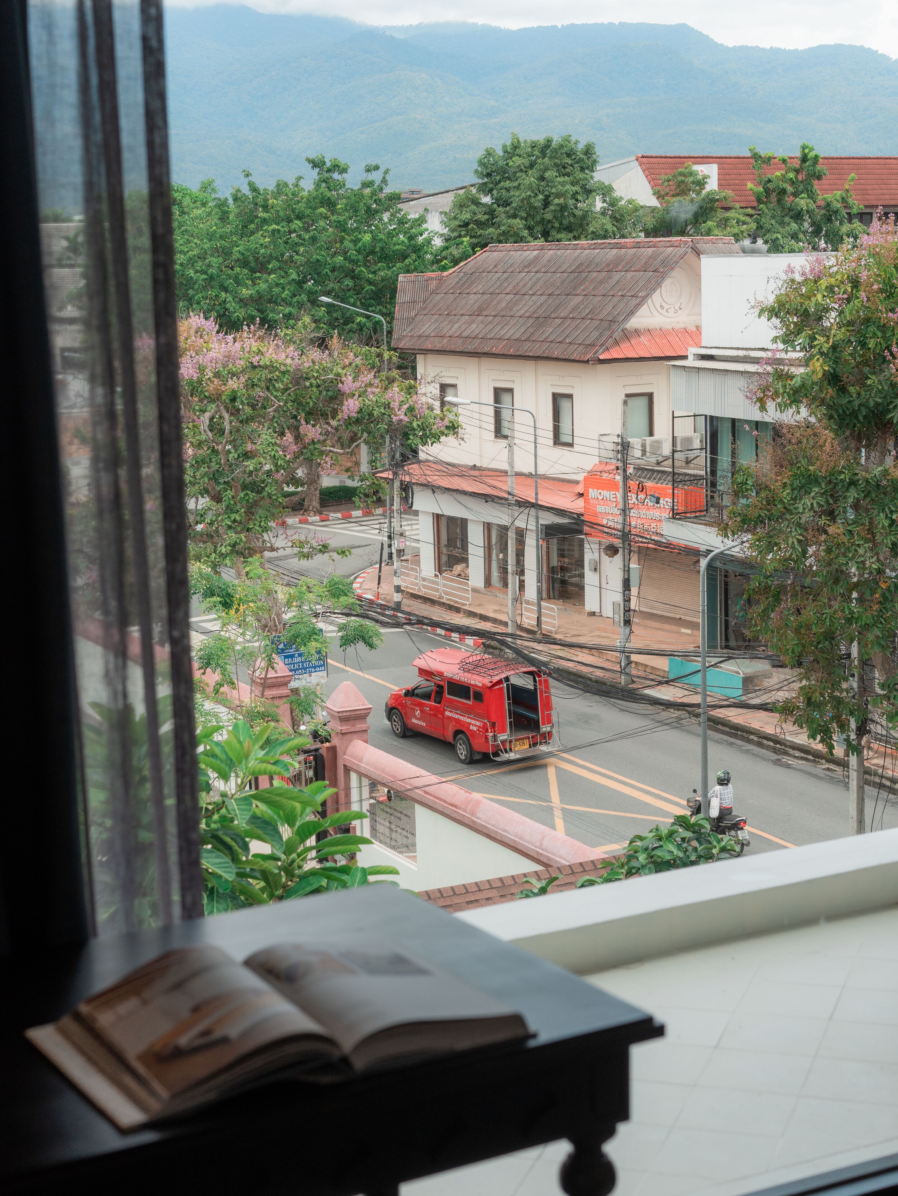 A view from a window overlooking a street with a red van and a motorbike.