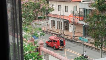A view from a window overlooking a street with a red van and a motorbike.
