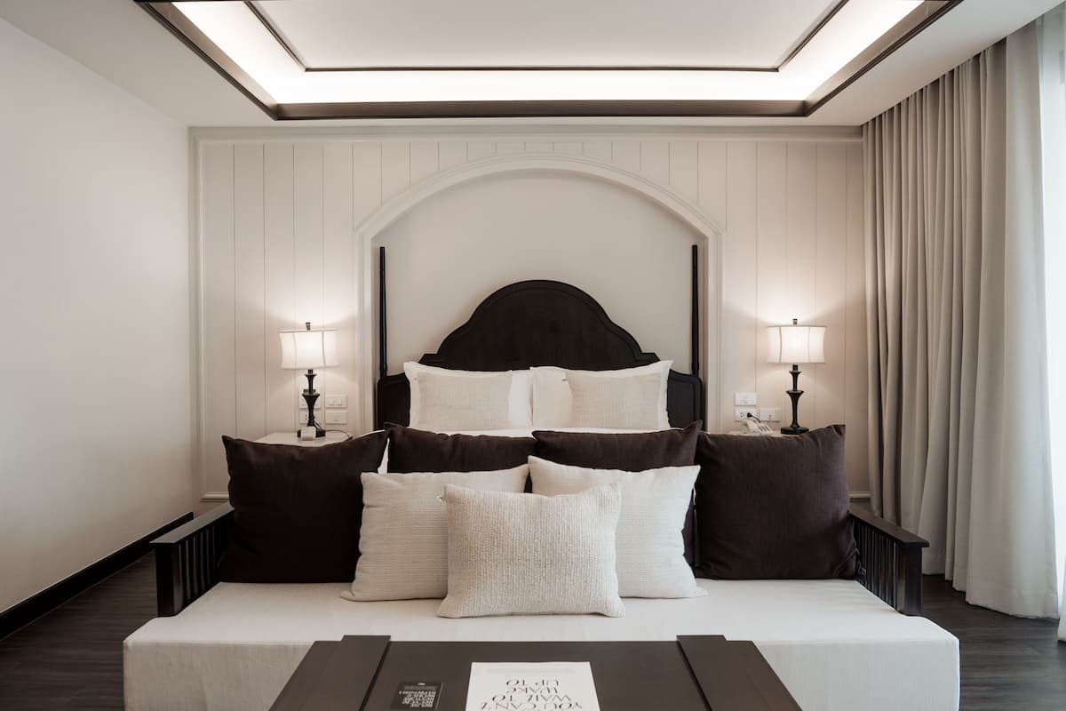 Quarto moderno com cama, luminárias de cabeceira, mesa de cabeceira e uma janela grande.