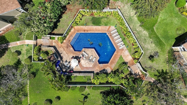 Vista aérea de uma piscina rodeada por um jardim com um espaço de pátio.
