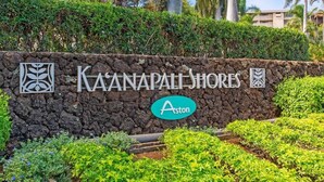 A sign for Kaanapali Shores with a logo and the word 'Aston' on a stone wall.