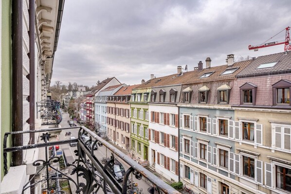 A row of colorful buildings with balconies, a street in the foreground, and a crane in the background.