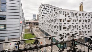 A modern urban building with a grid-like facade, a visible entrance, and a street view with bicycles and a pedestrian path.