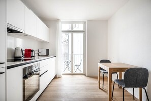 Una cocina moderna con armarios blancos, una mesa de comedor de madera y una silla gris.