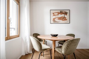 Un comedor con una mesa redonda de madera, cuatro sillas, un bol y un cuadro abstracto enmarcado en la pared.