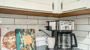 Una cocina con armarios blancos, una cafetera y un libro de cocina titulado 'Old World Italian'.