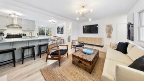 Une cuisine moderne dotée d’un îlot central, de tabourets de bar et d’un coin repas avec une table et des chaises en bois.