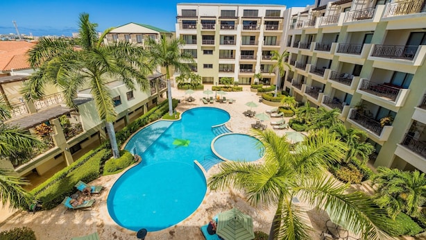 A hotel with a central swimming pool, multiple balconies, and lush landscaping. - One Bedroom w/ Amazing Views, GYM, Resort Amenities (Noord)