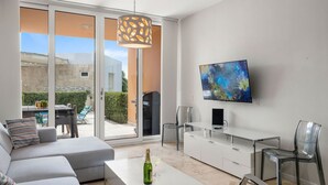 A modern living room with a sofa, a coffee table, a TV, and a dining area with a table and chairs.