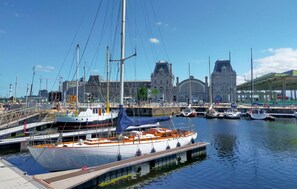 Un puerto deportivo con barcos amarrados, un puente y un edificio grande con una torre del reloj al fondo.