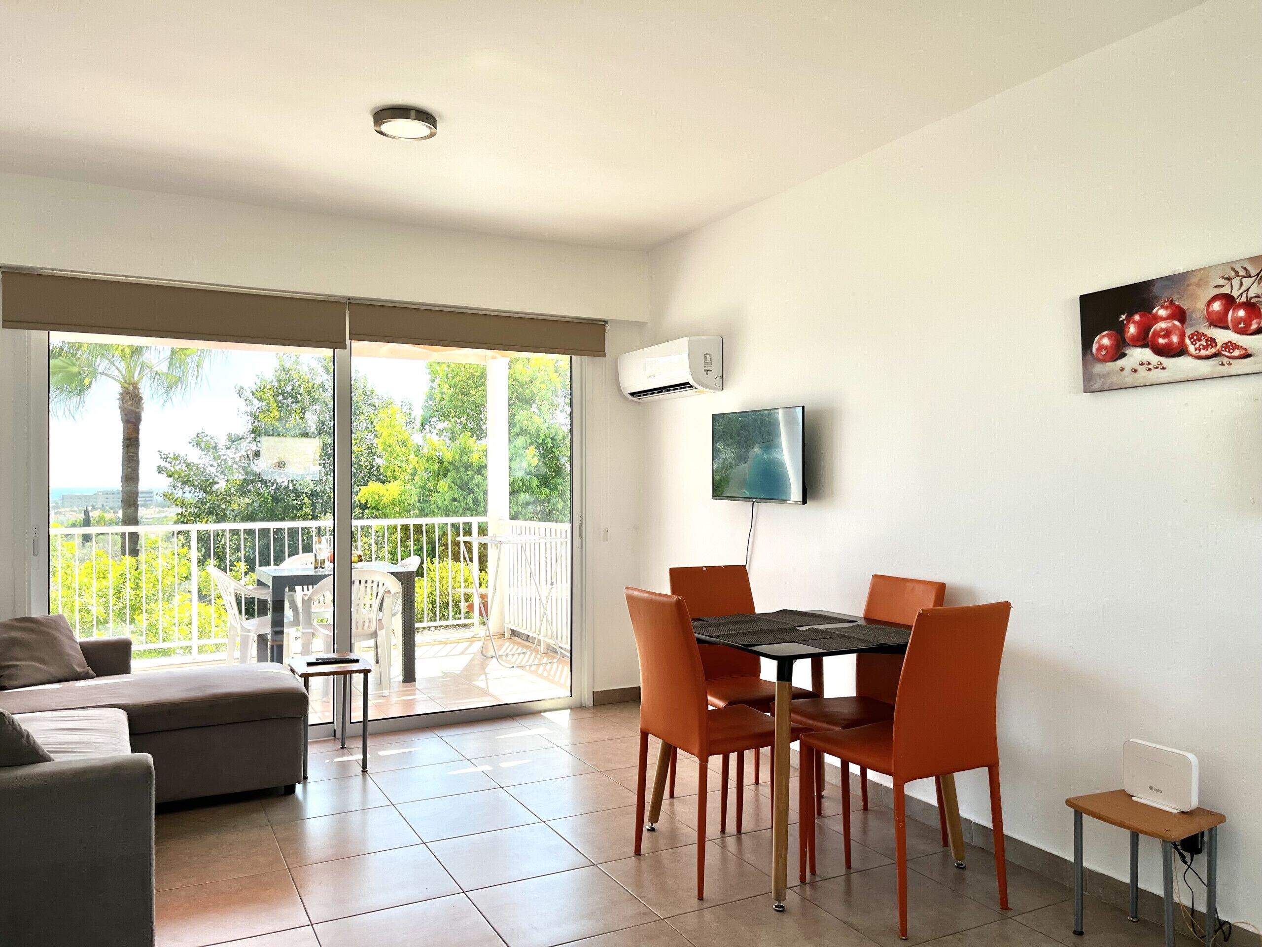 Una sala de estar moderna con balcón, comedor y televisor montado en la pared.