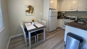 A modern kitchen with white cabinets, a stainless steel refrigerator, and a dining area with a table and chairs. - Cozy 1K & 1Q / 1b, 5 minutes walk to downtown (Lafayette)