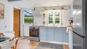 Eine kleine Küche mit Einbauofen, Spüle und Kühlschrank.