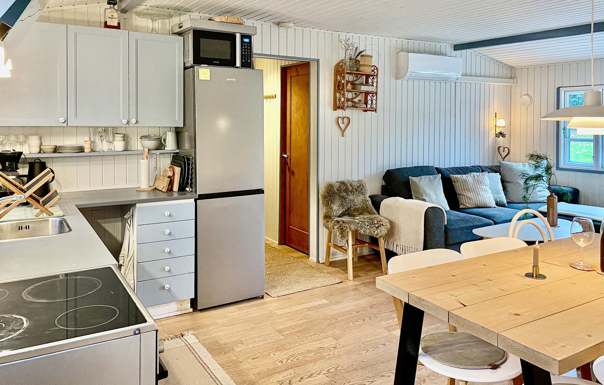 Eine kompakte Küche mit Kühlschrank, Mikrowelle und Herd. Angrenzend an die Küche befindet sich ein Essbereich mit Tisch und Stühlen.