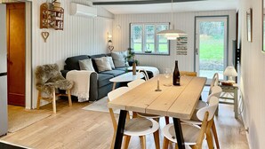 Ein gemütliches Wohnzimmer mit einer Couch, einem Esstisch mit Stühlen und einer Küchenzeile mit Fenster.