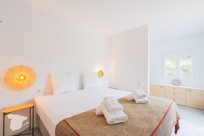 Une chambre d’hôtel comprenant un lit, une table de chevet, une lampe fixée au mur, une fenêtre avec vue et une armoire en bois.