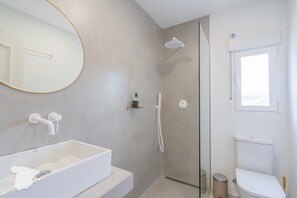 Ein modernes Badezimmer mit einer weißen Badewanne, einer Duschkabine aus Glas und einem WC.