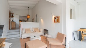 Un salon moderne avec un canapé, deux fauteuils, un téléviseur et une cheminée.