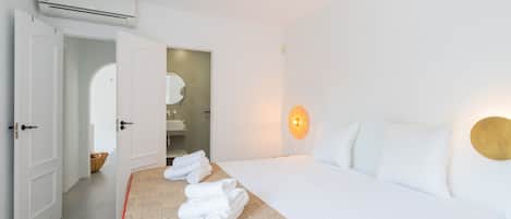 Una habitación de hotel con cama, baño y aire acondicionado.
