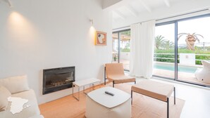 Ein modernes Wohnzimmer mit Kamin, Sitzgruppe und Blick auf einen Pool.