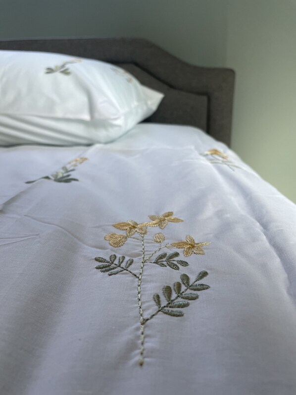 A bed with a white bedspread featuring embroidered floral designs. - Full sized home (Harpswell)