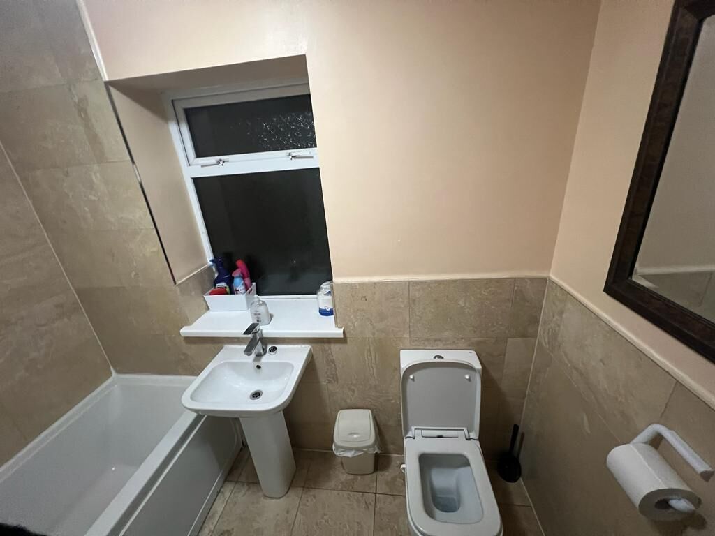 Un bany amb banyera, rentatge, vàter i una petita finestra.