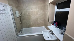A bathroom with a bathtub, a sink, and a window. - Remarkable 3-Bed House in Westcliff-on-Sea (Westcliff-on-Sea)