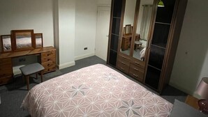 A bedroom with a bed, a desk, a chair, a wardrobe, and a mirror. - Remarkable 3-Bed House in Westcliff-on-Sea (Westcliff-on-Sea)
