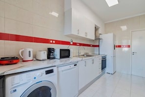 Kitchen equipped with a refrigerator, microwave, toaster, and washing machine.